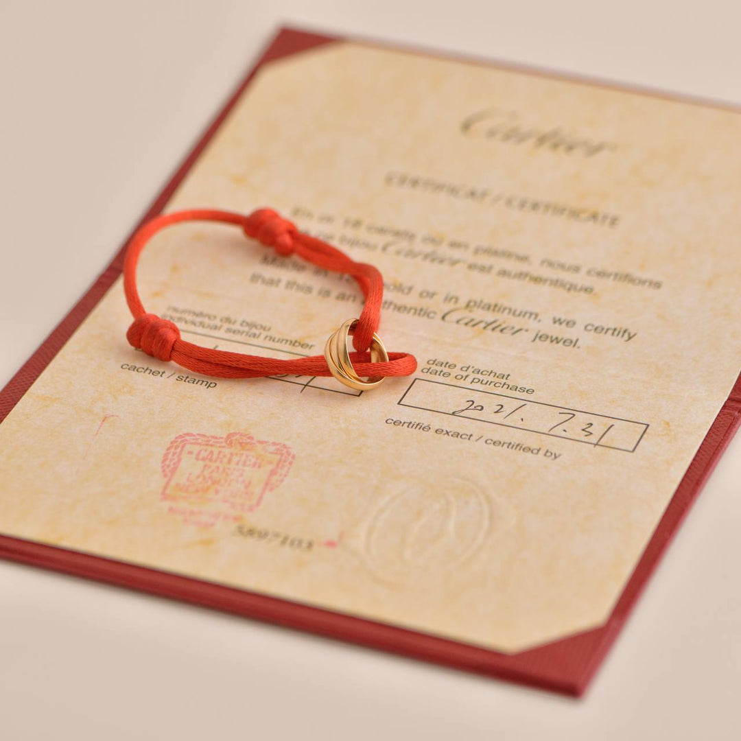 pre-loved Cartier Trinity 18K Rose Gold Bracelet on red silk cord.