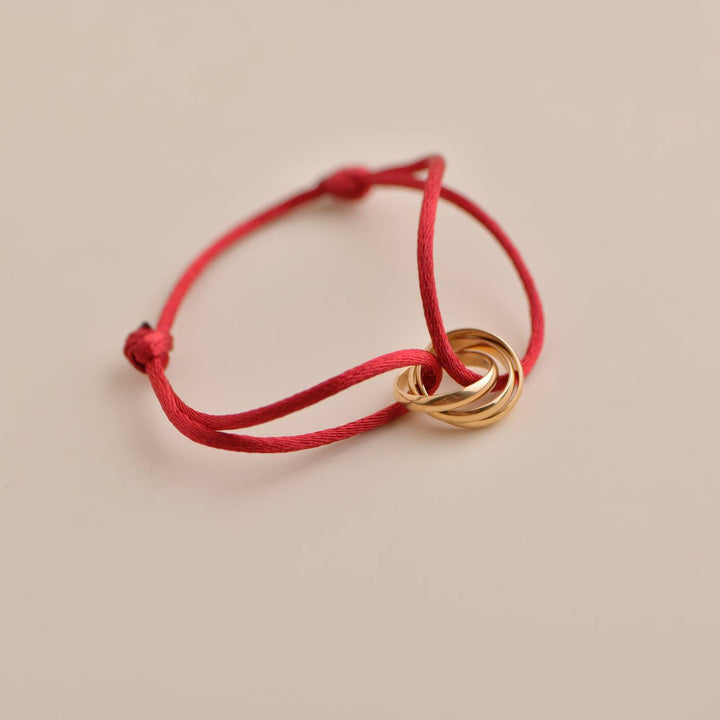 Pre-loved Cartier Trinity 18K Rose Gold Bracelet on vibrant red silk cord